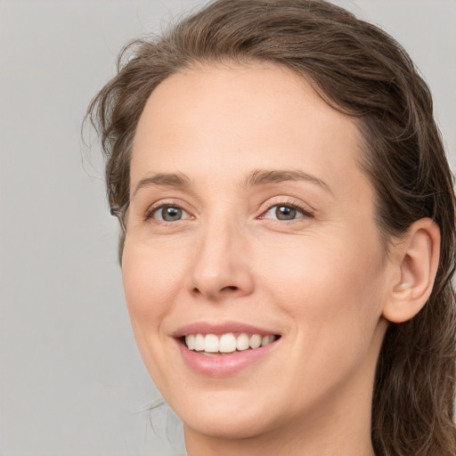 Joyful white young-adult female with long  brown hair and grey eyes