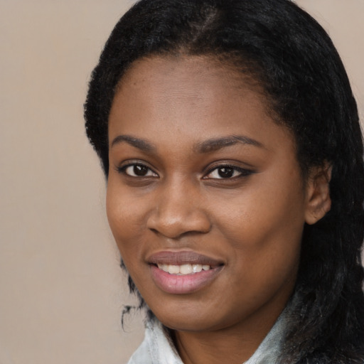 Joyful black young-adult female with long  black hair and brown eyes