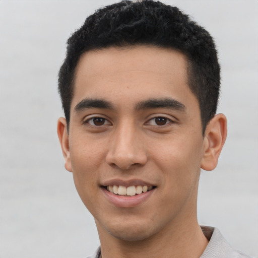 Joyful latino young-adult male with short  black hair and brown eyes