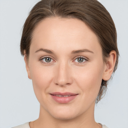 Joyful white young-adult female with medium  brown hair and grey eyes