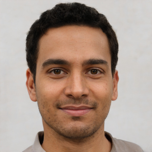 Joyful latino young-adult male with short  brown hair and brown eyes