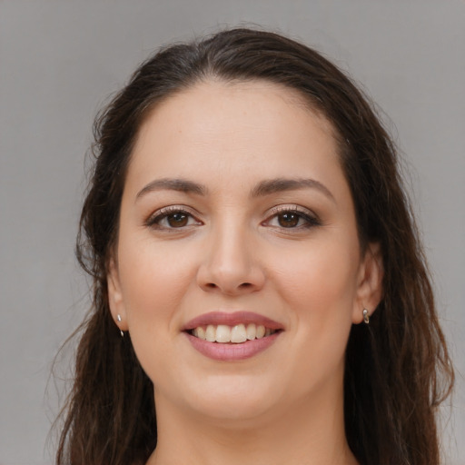 Joyful white young-adult female with long  brown hair and brown eyes