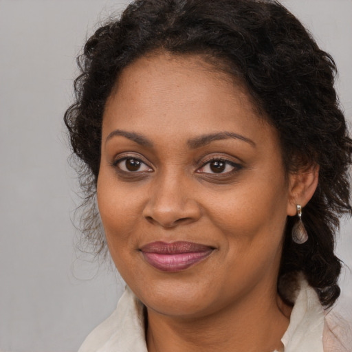 Joyful black adult female with medium  brown hair and brown eyes