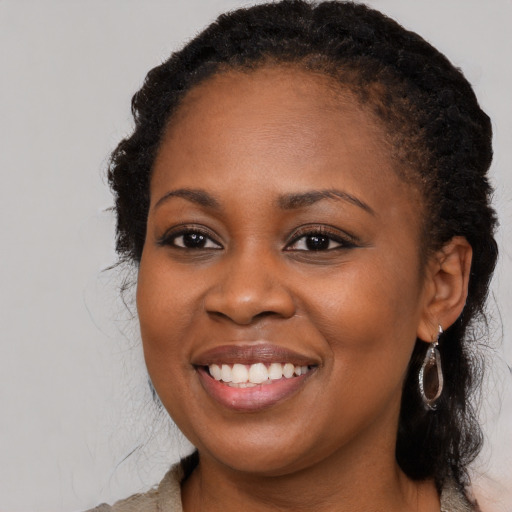 Joyful black young-adult female with long  brown hair and brown eyes
