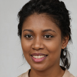 Joyful black young-adult female with long  brown hair and brown eyes