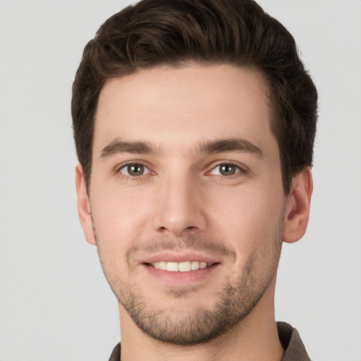 Joyful white young-adult male with short  brown hair and grey eyes