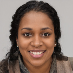 Joyful black young-adult female with long  brown hair and brown eyes