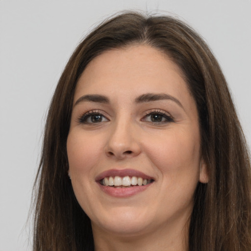 Joyful white young-adult female with long  brown hair and brown eyes