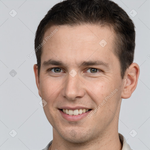 Joyful white young-adult male with short  brown hair and grey eyes