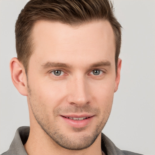 Joyful white young-adult male with short  brown hair and grey eyes