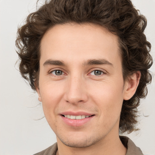 Joyful white young-adult male with medium  brown hair and green eyes