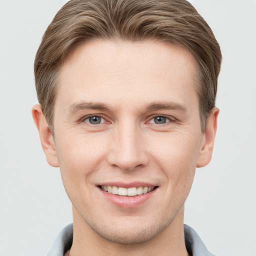 Joyful white young-adult male with short  brown hair and grey eyes