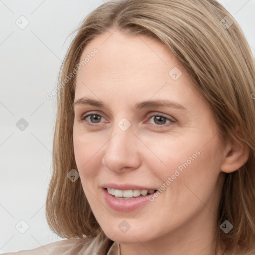 Joyful white young-adult female with long  brown hair and blue eyes