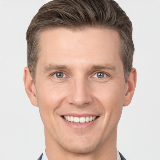 Joyful white young-adult male with short  brown hair and grey eyes