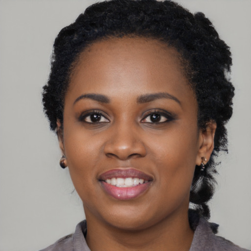 Joyful black young-adult female with long  black hair and brown eyes