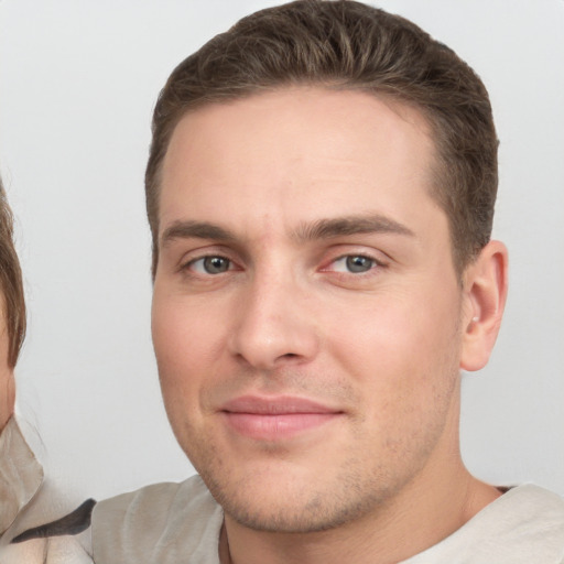 Joyful white young-adult male with short  brown hair and grey eyes