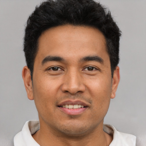 Joyful latino young-adult male with short  brown hair and brown eyes