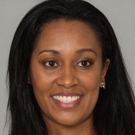 Joyful black young-adult female with long  brown hair and brown eyes
