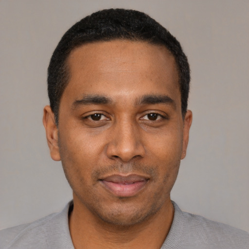 Joyful black young-adult male with short  black hair and brown eyes