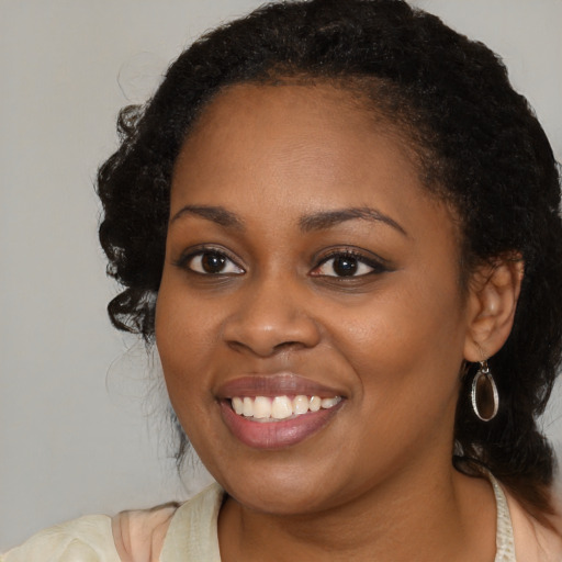 Joyful black young-adult female with long  brown hair and brown eyes