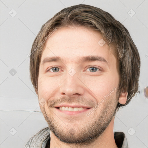 Joyful white young-adult male with short  brown hair and grey eyes