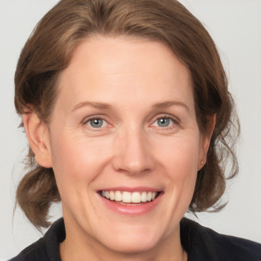 Joyful white adult female with medium  brown hair and grey eyes