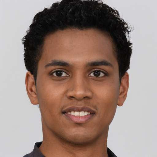 Joyful black young-adult male with short  black hair and brown eyes