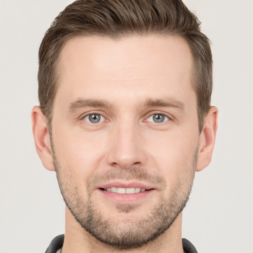 Joyful white young-adult male with short  brown hair and grey eyes