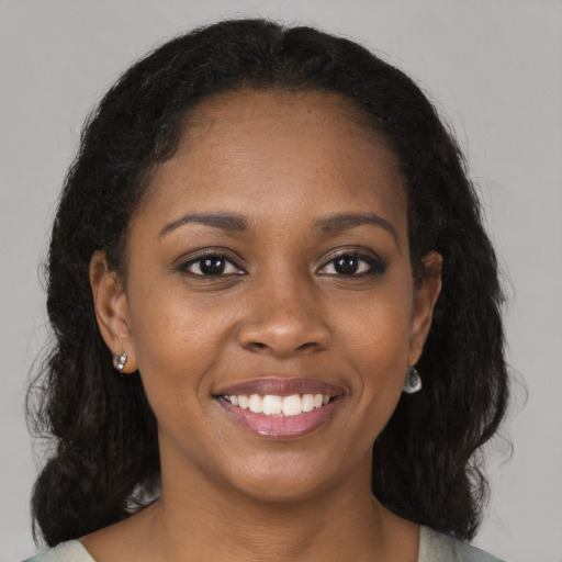 Joyful black young-adult female with long  brown hair and brown eyes