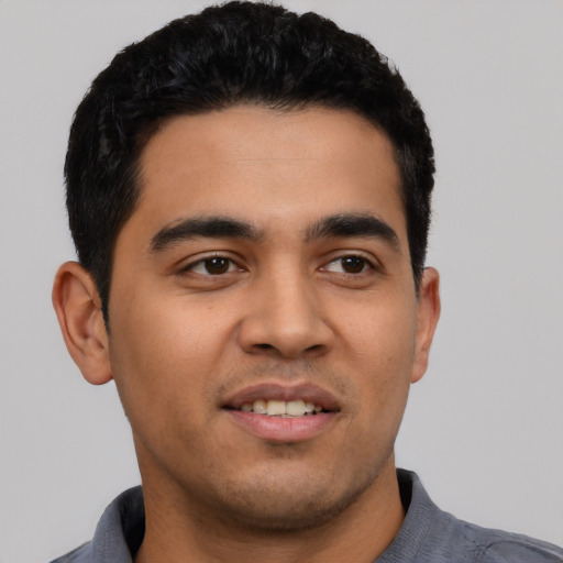 Joyful latino young-adult male with short  black hair and brown eyes