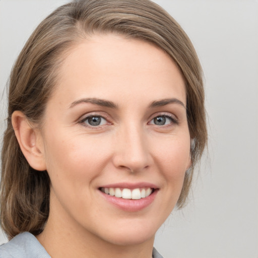 Joyful white young-adult female with medium  brown hair and grey eyes