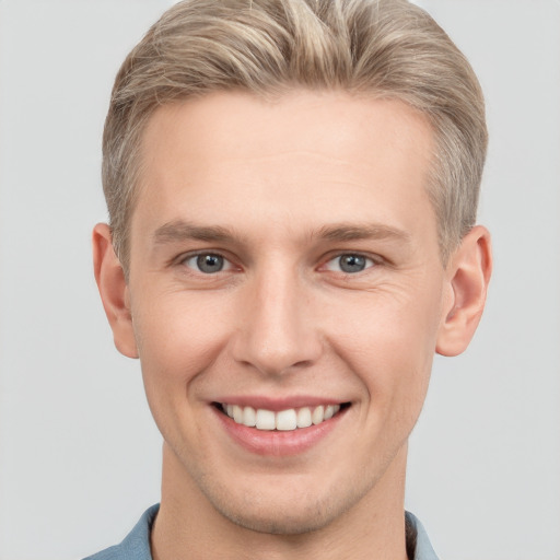 Joyful white young-adult male with short  brown hair and grey eyes