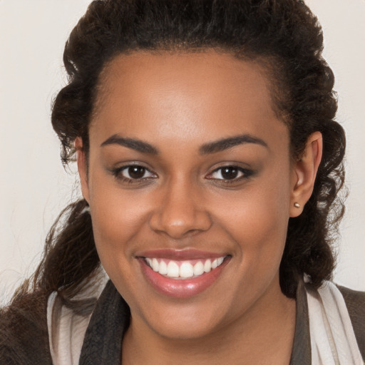 Joyful black young-adult female with long  brown hair and brown eyes