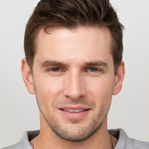 Joyful white young-adult male with short  brown hair and grey eyes