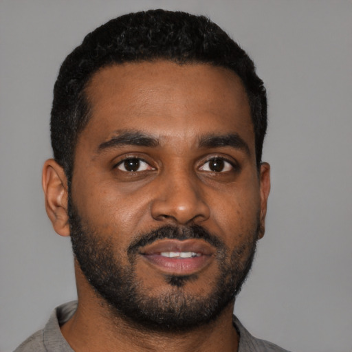 Joyful black young-adult male with short  black hair and brown eyes