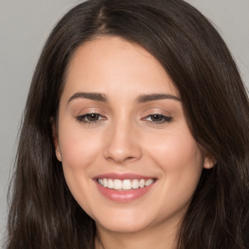 Joyful white young-adult female with long  brown hair and brown eyes