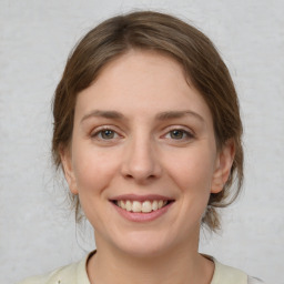 Joyful white young-adult female with medium  brown hair and grey eyes