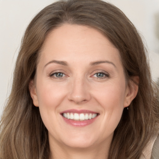 Joyful white adult female with long  brown hair and grey eyes