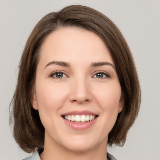 Joyful white young-adult female with medium  brown hair and green eyes