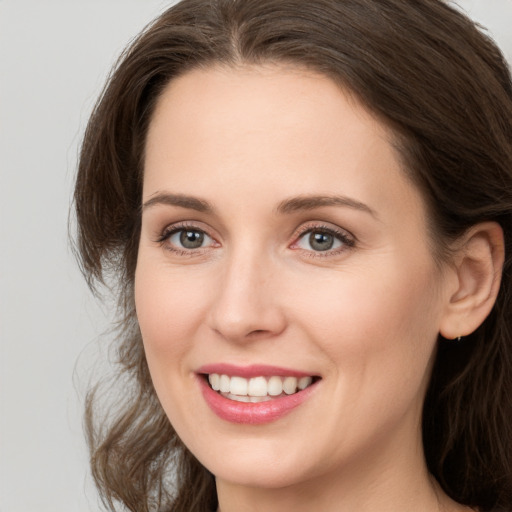 Joyful white young-adult female with long  brown hair and grey eyes