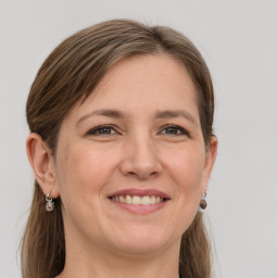 Joyful white adult female with long  brown hair and grey eyes