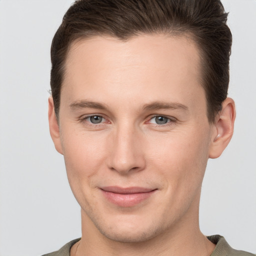 Joyful white young-adult male with short  brown hair and grey eyes