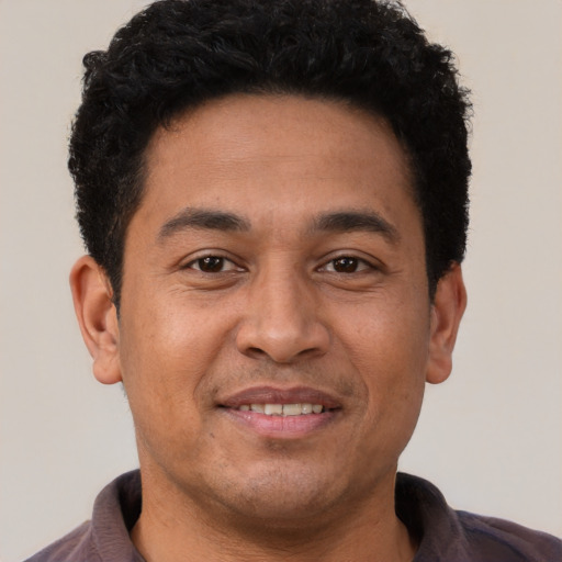 Joyful latino young-adult male with short  brown hair and brown eyes