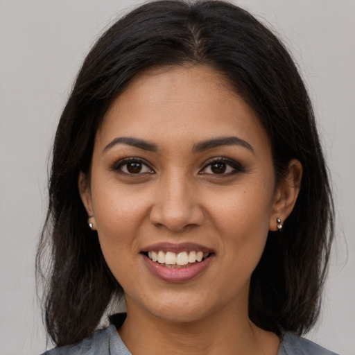 Joyful latino young-adult female with long  brown hair and brown eyes