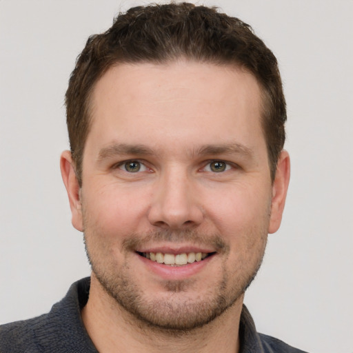 Joyful white young-adult male with short  brown hair and grey eyes