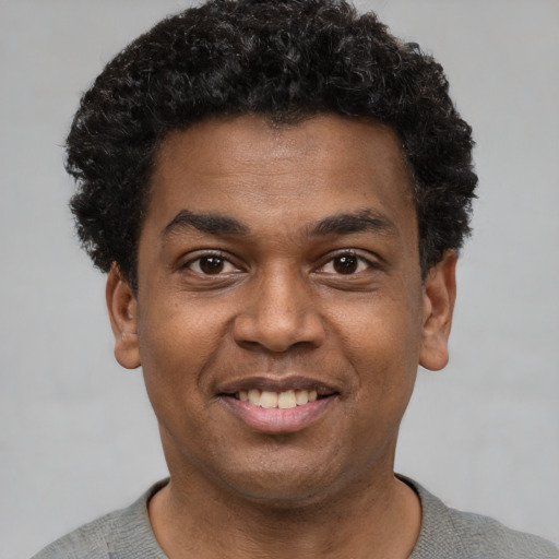 Joyful black young-adult male with short  black hair and brown eyes