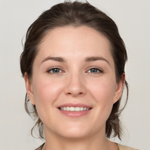 Joyful white young-adult female with medium  brown hair and grey eyes