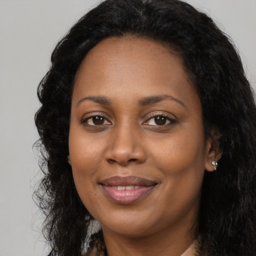 Joyful black young-adult female with long  black hair and brown eyes