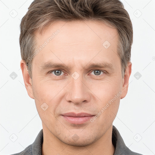 Joyful white young-adult male with short  brown hair and grey eyes