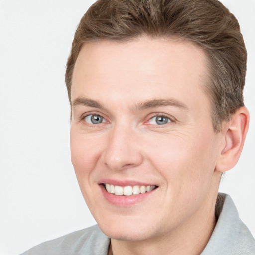 Joyful white young-adult male with short  brown hair and grey eyes